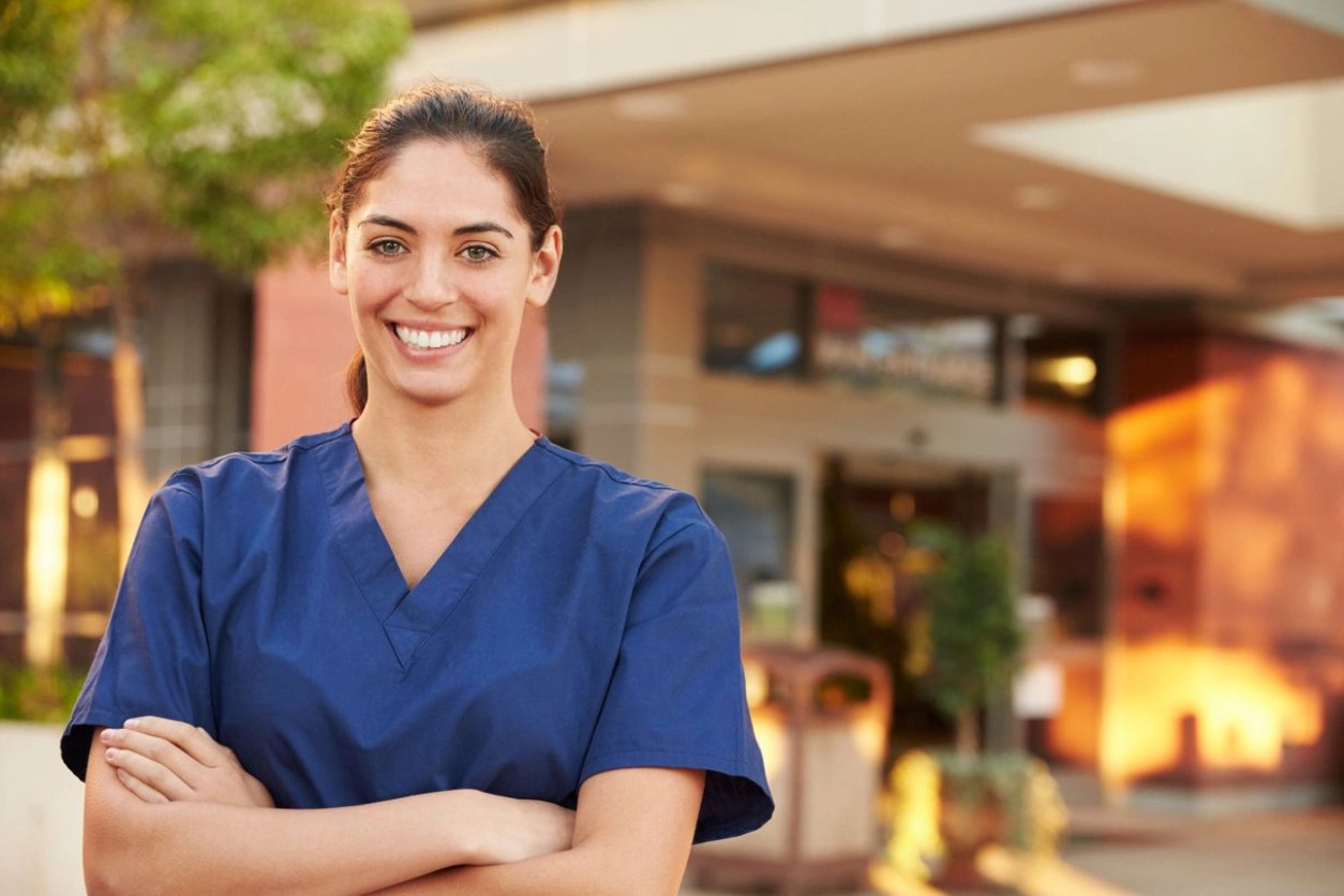 A woman in scrubs standing outside of a building.